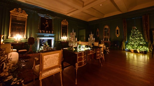 Dark historic room with gold furniture and frames and twinkly candelabras and Christmas tree